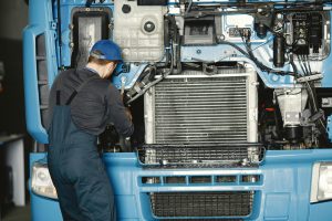 Man-in-Black-Uniform-and-Blue-Cap-Fixing-Blue-Truck